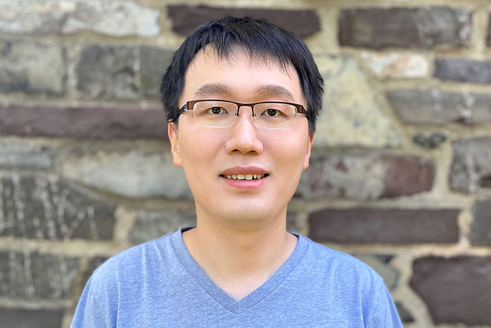 Haowei Xu in a pale blue tshirt photographed against a stone wall, MIT