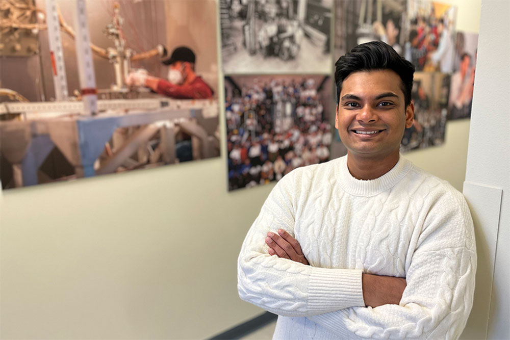 male student standing with arms folded, grid of photos of people in labs in the background, MIT