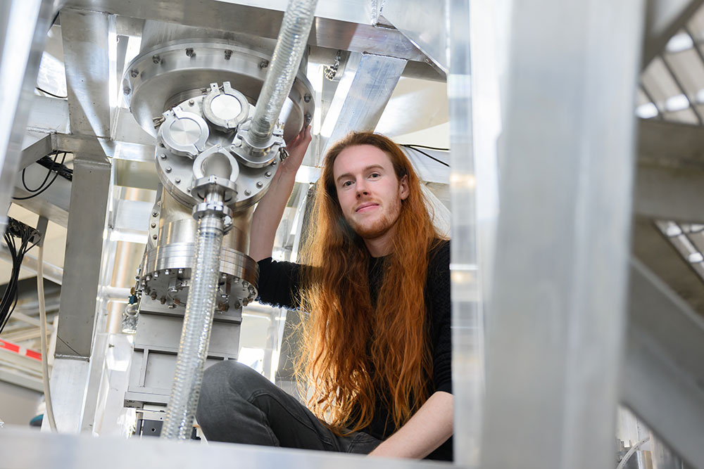 Graduate student, Thomas Varnish, in the middle of a research facility, PUFFIN at MIT's PSFC